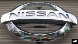 FILE - Vehicles are reflected on the logo of Nissan Motors at a showroom in Tokyo's Ginza shopping district, Japan.