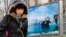 Woman walks past a poster showing an offshore work platform from of China National Offshore Oil Corp. (CNOOC), outside its Beijing headquarters, Dec. 2012 file photo.