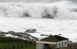 FILE - A wave breaks in front of a house on the coast of La Guardia, northern Spanish region of Galicia, Feb. 6, 2014.