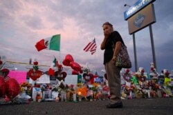 FILE - Catalina Saenz wipes tears from her face as she visits a makeshift memorial near the scene of a mass shooting at a shopping complex, Aug. 6, 2019, in El Paso, Texas.
