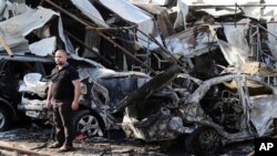 FILE - A man inspects site of car bomb explosion in Baghdad's eastern Mashtal neighborhood, Iraq, Nov. 17, 2014.