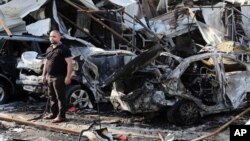 Man inspects site of car bomb explosion in Baghdad's eastern Mashtal neighborhood, Iraq, Nov. 17, 2014.