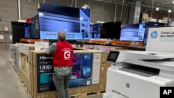 An associate checks over a big-screen television on display in a Costco warehouse Feb. 6, 2024, in Colorado Springs, Colorado. The U.S. Labor Department reported on Feb. 13 that the consumer price index rose 0.3% from December to January.