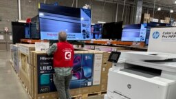 An associate checks over a big-screen television on display in a Costco warehouse Feb. 6, 2024, in Colorado Springs, Colorado. The U.S. Labor Department reported on Feb. 13 that the consumer price index rose 0.3% from December to January.