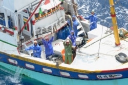 FILE - Taiwanese fishermen wave on a fishing boat as they operate on waters near Ishigaki island, Okinawa prefecture, in this photo taken by Kyodo, May 10, 2013.