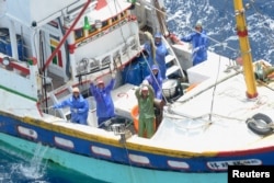 Nelayan Taiwan melambai di atas kapal penangkap ikan saat mereka beroperasi di perairan dekat Pulau Ishigaki, prefektur Okinawa, 10 Mei 2013. (Foto: Kyodo via Reuters)