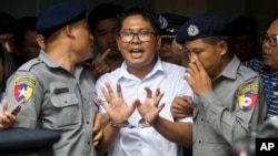 Reuters journalist Wa Lone, center, talks to journalists as he is escorted by police to leave a court in Yangon, Myanmar, Sept. 3, 2018.