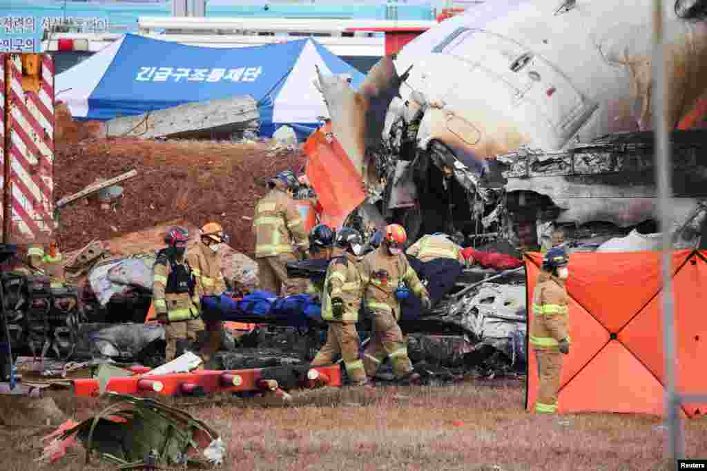 Los bomberos transportan el cuerpo de un pasajero de los restos de un avión de Jeju que se estrelló tras salirse de la pista en el Aeropuerto Internacional de Muan, en Muan, Corea del Sur, el 29 de diciembre de 2024.