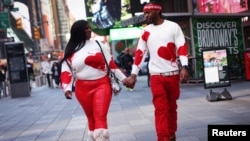 Una pareja con suéteres a juego con el tema del corazón camina de la mano por Times Square el día de San Valentín en la ciudad de Nueva York, el 14 de febrero de 2023. REUTERS/Mike Segar