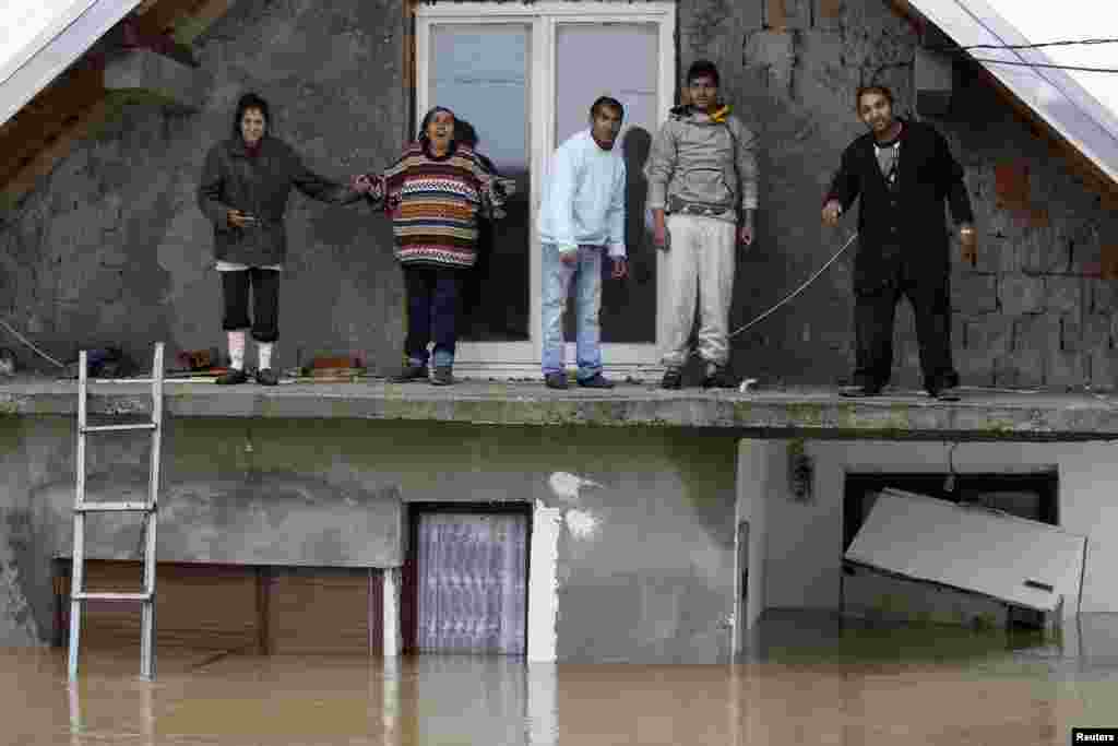 Orang-orang berdiri di teras rumah mereka yang kebanjiran menunggu untuk dievakuasi di kota Obrenovac, di sebelah timur Belgrade, Serbia. &nbsp;