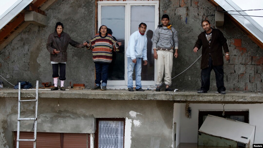 Warga berdiri di balkon lantai atas rumah mereka yang kebanjiran, menunggu dievakuasi dari kota Obrenovac, sebelah timur Belgrad, Serbia (16/5). (Reuters/Marko Djurica)