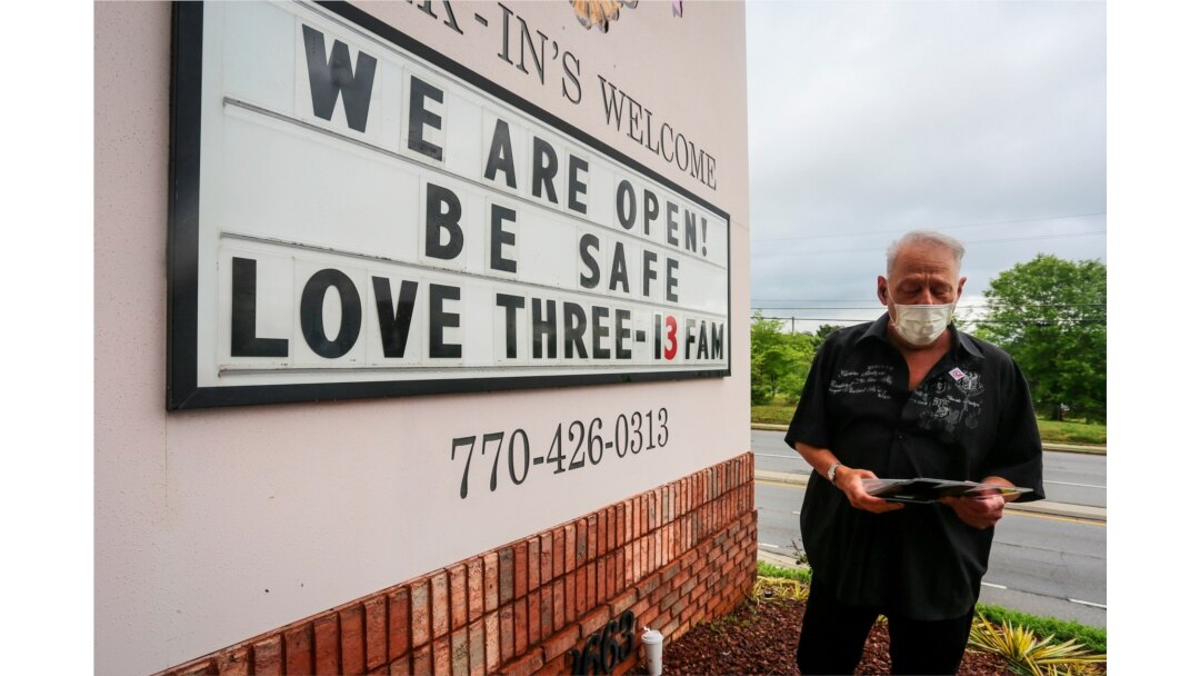 Lester Crowell, managing partner of Three-13 Salon, Spa & Boutique in Marietta, Ga., changes the letters of the salon's sign, April 24, 2020.