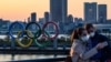 Dua orang yang mengenakan masker mengambil swafoto di depan Olympic Rings, di taman Odaiba Seaside, Tokyo yang akan menjadi lokasi Olimpiade 2020 (foto: dok).