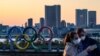 Des visiteurs portent des masques faciaux devant les anneaux olympiques au parc de bord de mer d'Odaiba à Tokyo, le 6 mars 2020. (Photo: Reuters)