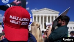 Seorang pendukung anti-aborsi yang mengenakan topi Make America Great Again berada di antara kumpulan aktivis hak aborsi yang menggelar aksi di luar gedung Mahkamah Agung AS di Washington, pada 24 Juni 2024. (Foto: Reuters/Nathan Howard)