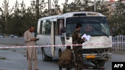 Afghan security personnel investigate a damage bus carrying employees of Khurshid TV, at the site of a bomb blast in Kabul, August 4, 2019.