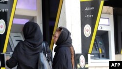 In this file photo taken on May 20, 2019, Iranian women use automated teller machines (ATM) in Tehran. The Trump administration on Oct. 8, 2020, imposed sweeping sanctions on Iran's banking sector.