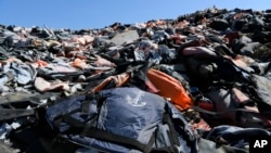 FILE - Piles of life jackets used by refugees and migrants lie at a dump in Molyvos village, near Lesbos, Greece. The Minnesota-based company Epimonia uses the life jackets to make bracelets that are sold to raise funds to help refugees and immigrants.