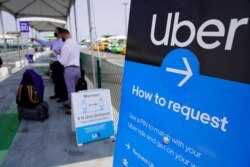 Travelers request an Uber ride at Los Angeles International Airport's LAX-it pick up terminal Thursday, Aug. 20, 2020. An appeals court has allowed ride-hailing giants Uber and Lyft to continue treating their drivers as independent contractors in…