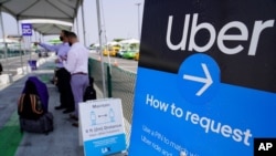 Des voyageurs demandent une course Uber au terminal de prise en charge LAX-it de l'aéroport international de Los Angeles, jeudi 20 août 2020.