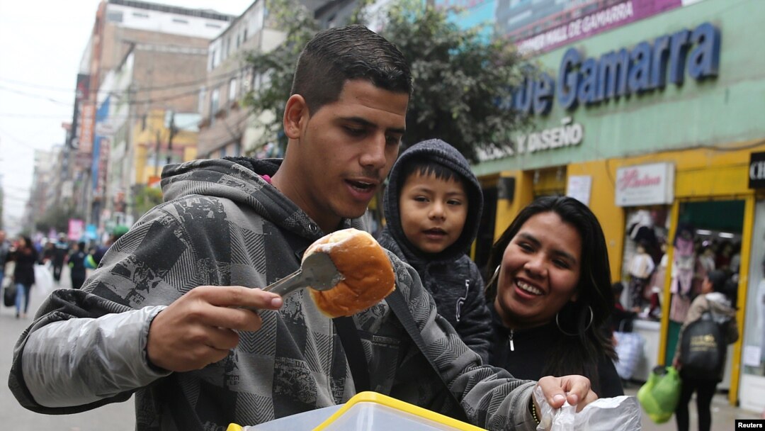 FILE - Bryant Medina, a migrant from Venezuela, sells traditional Venezuelan pastry known as bombas venezolanas at the La Victoria district in Lima, Peru, Aug. 23, 2017. 