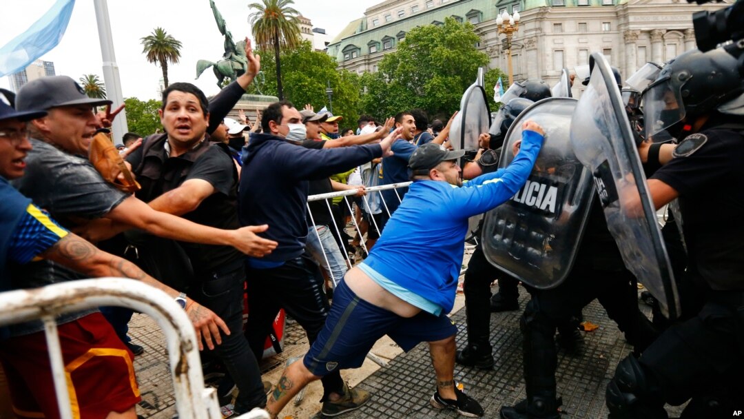 Soccer fans waiting to see Diego Maradona lying in state clash with police outside the presidential palace in Buenos Aires, Argentina, Nov. 26, 2020.