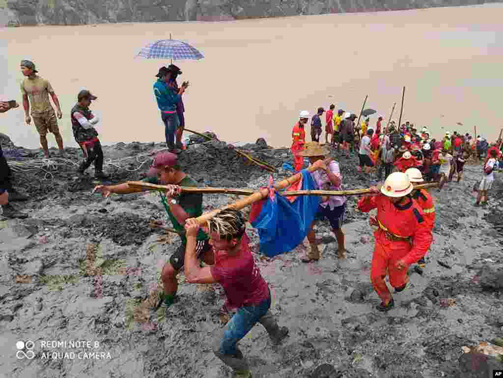 In this photo released from Myanmar Fire Service Department, rescuers carry a recovered body of a victim of a landslide from a jade mining area in Hpakant, Kachin state, northern Myanmar.