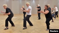 FILE - Seniors practice tai chi in a cultural center in Brussels, June 28, 2017.