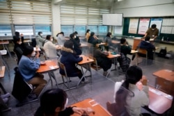 Students wearing face masks wait for the start of the annual college entrance examination amid the coronavirus pandemic at an exam hall in Seoul, South Korea, Dec. 3, 2020.