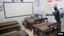 Petugas menyemprotkan cairan desinfektan di ruang kelas di sebuah sekolah di Surabaya (foto VOA/Petrus Riski).