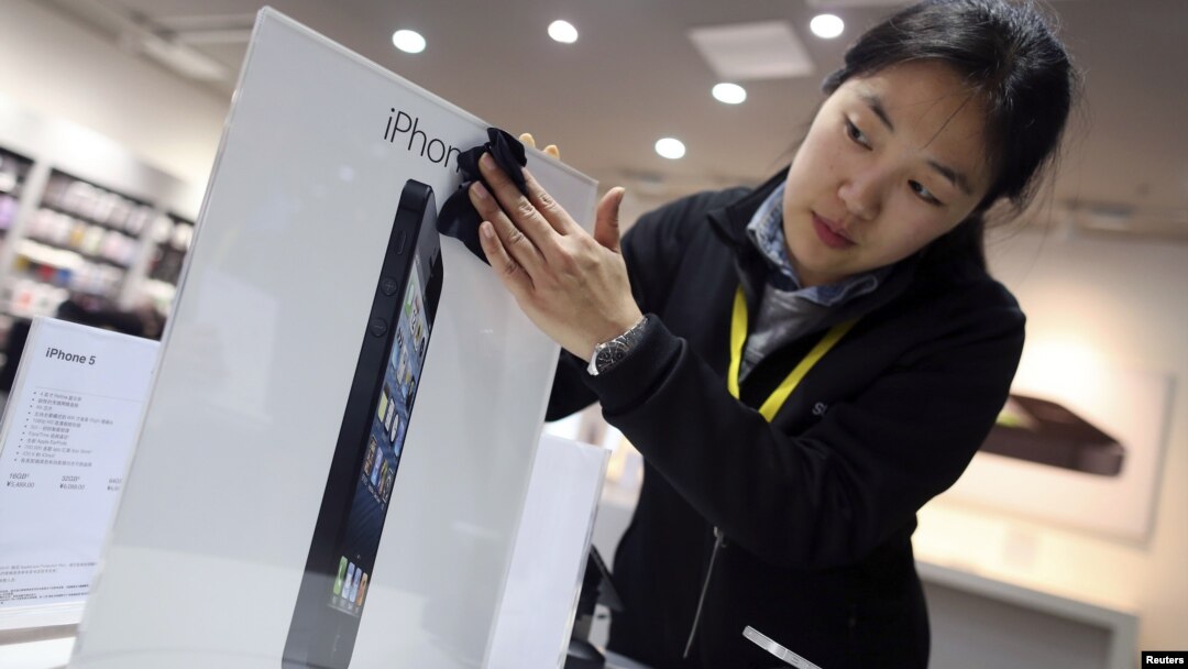 Seorang pegawai toko di Wuhan, provinsi Hubei, Tiongkok, membersihkan papan iklan iPhone 5. (Foto: Reuters)