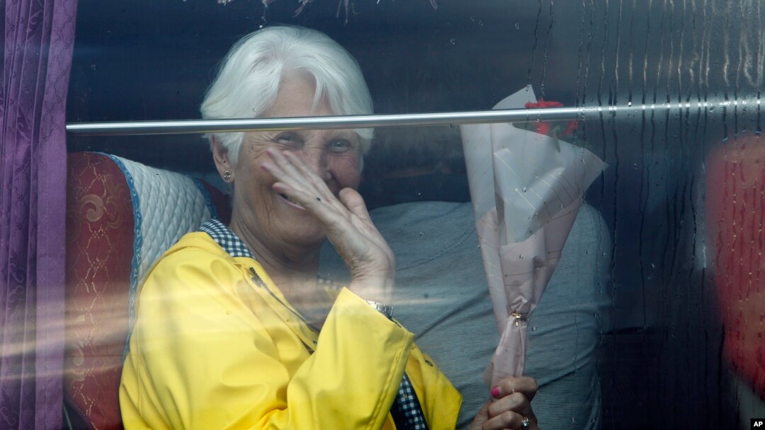 A passenger waves from a bus after she disembarked from the Westerdam, owned by Holland America Line, at the port of Sihanoukville, Cambodia, Feb. 14, 2020.