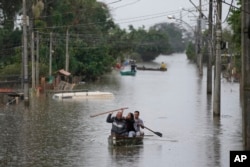 Residents paddle across a flooded area after heavy rain in Canoas, Rio Grande do Sul state, Brazil, on May 10, 2024.