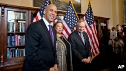 El recién electo senador Cory Booker (izquierda) y su madre, Carolyn, junto al líder de la mayoría demócrata Harry Reid, luego de su juramentación.