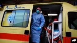 A paramedic wearing a suit to protect against coronavirus, closes the door of an ambulance at Evangelismos hospital in Athens, Nov. 12, 2020.