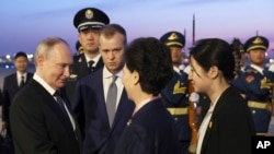 Russian President Vladimir Putin, left, shakes hands with Chinese State Councilor Shen Yiqin, second right, upon his arrive at the Beijing Capital International Airport in Beijing, China, May 16, 2024. 