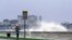 A jogger makes his way along Bayshore Blvd., in Tampa, Fla. as a wave breaks over a seawall, during the aftermath of Tropical Storm Elsa, July 7, 2021. 