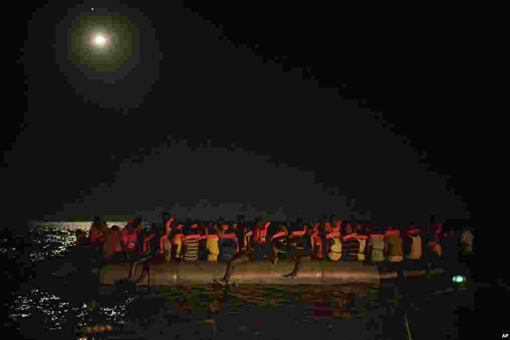 African migrants wait to be assisted by crew members of the Louise Michel and Astral rescue vessels, after being located sailing adrift on an overcrowded rubber boat, 70 miles southwest Malta, in the Central Mediterranean sea, Aug. 29, 2020.