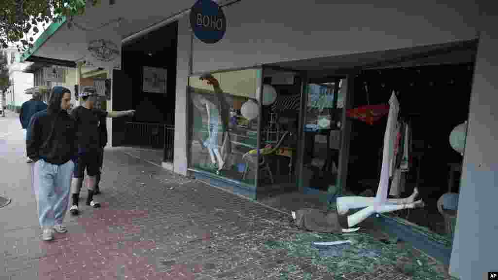 People walk past a tumbled mannequin and broken storefront window on First Street following an earthquake in Napa, California, Aug. 24, 2014.