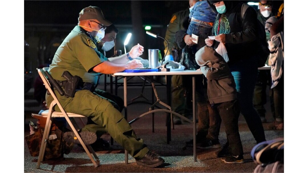 A child rests its head on a table as a U.S. Customs and Border Protection officer processes migrants who crossed into the U.S., March 24, 2021, in Roma, Texas.
