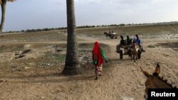 FILE - People walk toward the border with Central African Republic in Um Dafuq, Sudan, May 29, 2017. 