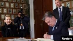 Nobel Peace Prize laureate Colombian President Juan Manuel Santos signs a protocol in the Norwegian Nobel Institute in Oslo, Norway, Dec. 9, 2016. Behind him are Colombian first lady Maria Clemencia Rodriguez and director of the Nobel Institute, Olav Njoelstad. 