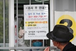 A man reads posted directions to receive the COVID-19 testing at a makeshift clinic in Seoul, South Korea, Aug. 20, 2020.