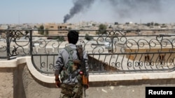 FILE - A Kurdish fighter from the People's Protection Units looks at the damage after an coalition airstrike in Raqqa, Syria, June 16, 2017. 