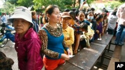 Cambodian villagers line up to cast their vote in the country's national election at a polling station at Chak Angre Leu pagoda, in Phnom Penh, Cambodia, Sunday, July 28, 2013. 