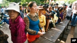 Cambodian villagers line up to cast their vote in the country's national election at a polling station at Chak Angre Leu pagoda, in Phnom Penh, Cambodia, Sunday, July 28, 2013. 