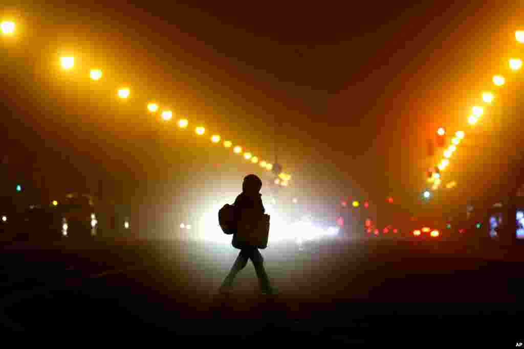 A woman crosses a road early morning in Munich. Germany has entered a harder lockdown, closing shops and schools in an effort to bring down stubbornly high new cases of the coronavirus.