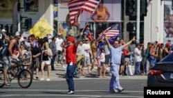 Warga AS keluar rumah dan menyerukan pembukaan kembali negara bagian California dalam aksi unjuk rasa di Huntington Beach, California Jumat (1/5).