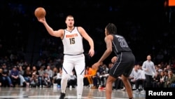 Nikola Jokic (15) de Denver passe le ballon contre l'attaquant de Brooklyn Noah Clowney (21), USA, le 29 octobre 2024.