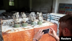 A visitor takes a picture of gas masks at a former base of the Soviet army, near the Chernobyl Nuclear Power Plant.